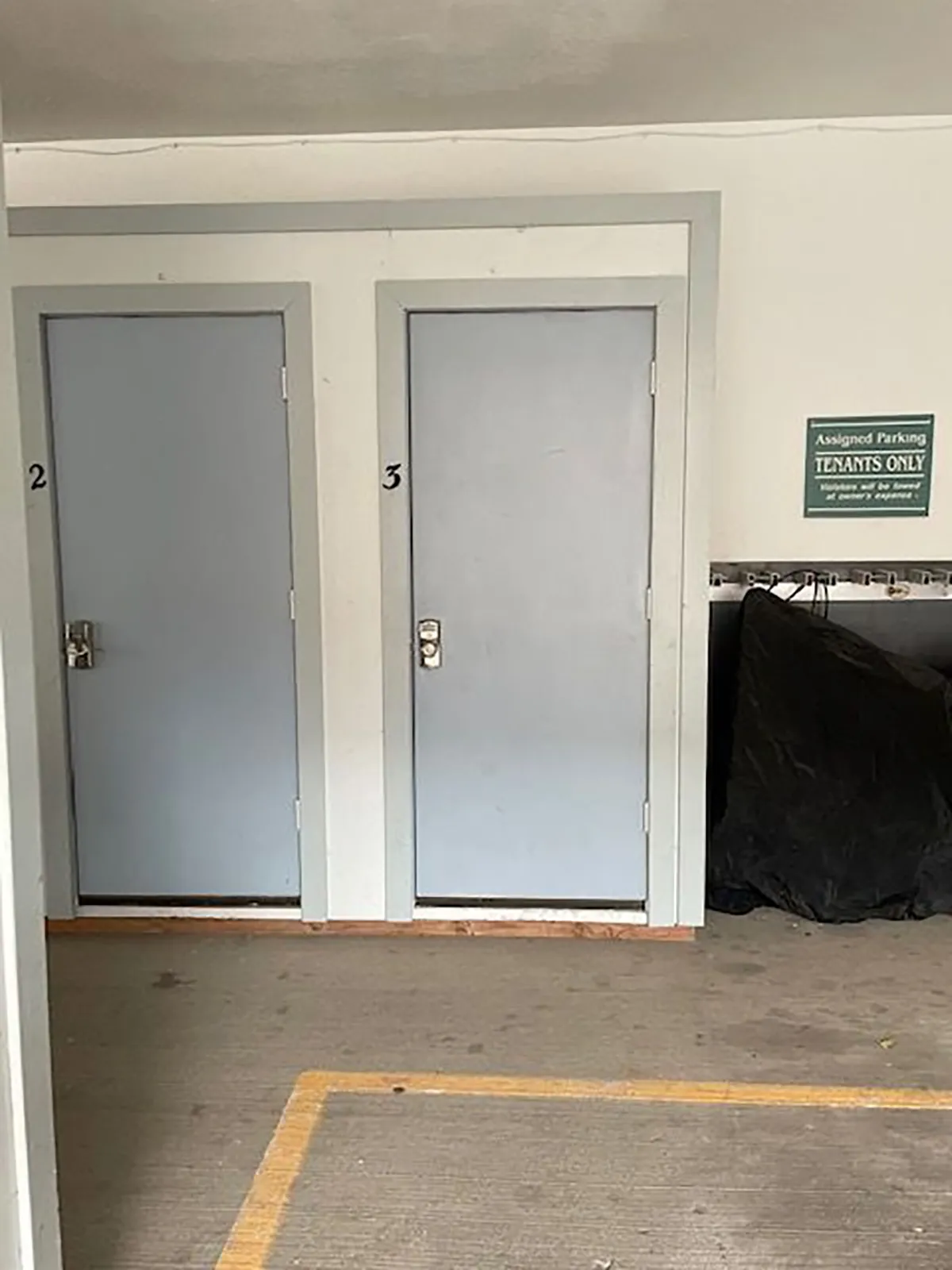 A practical interior hallway showcases two doors labeled '2' and '3' and an assigned parking sign, highlighting the convenience of on-site parking and organized spaces for residents or guests.